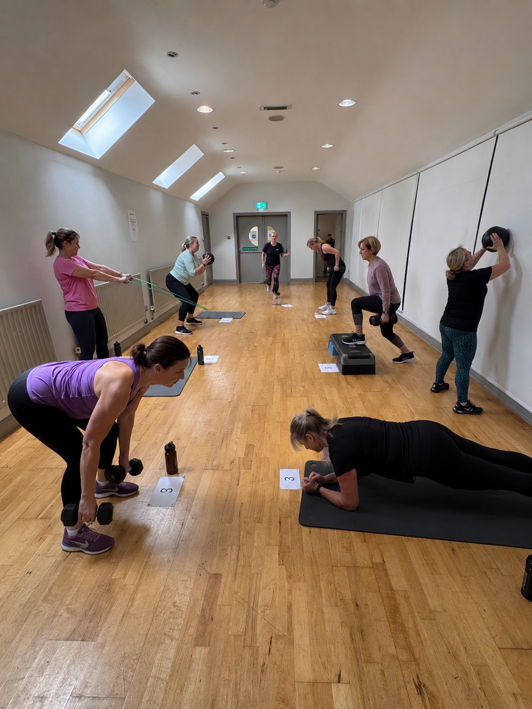 Women training together in a small-group strength circuit